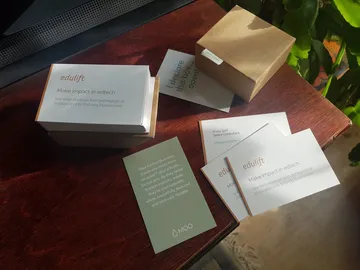 Philip Seifi's orange and white EduLift business cards, with the words Make impact in edtech.