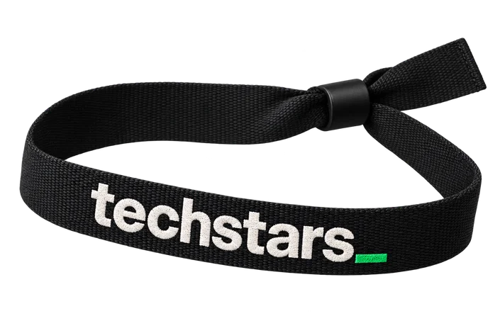 A black woven wristband bearing the Techstars wordmark and green underscore